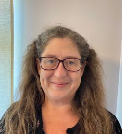 Professor Louise Tracey, a smiling woman with long brown hair and glasses.